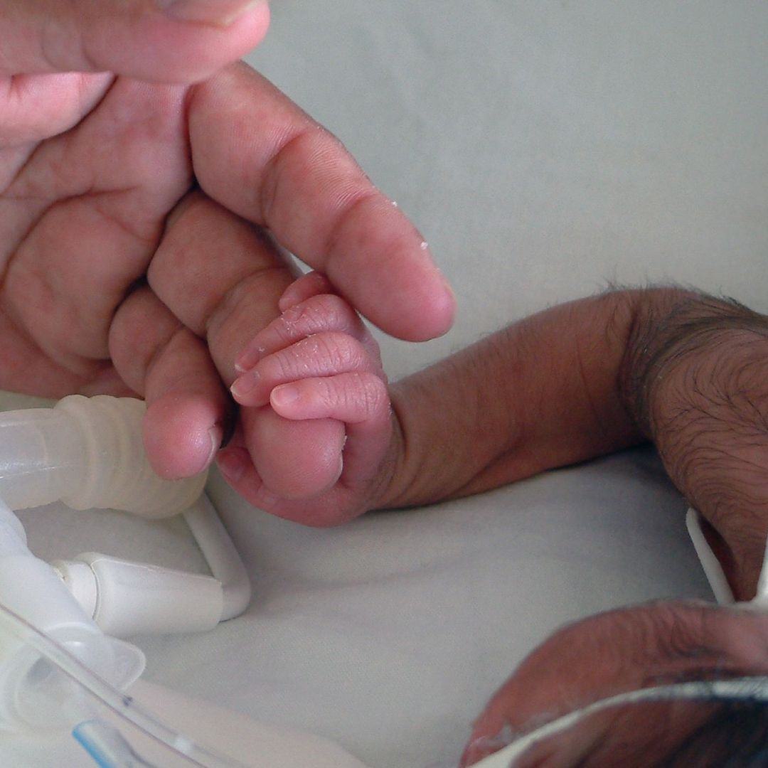 Padre de familia toma de la mano a un bebé recién nacido